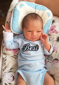 Portrait of cute baby girl sitting on bed at home