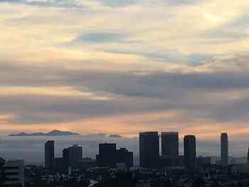 View of cityscape against cloudy sky