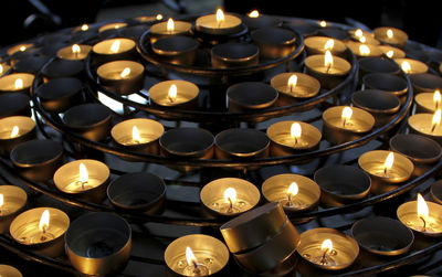 High angle view of illuminated tea lights on stand at night