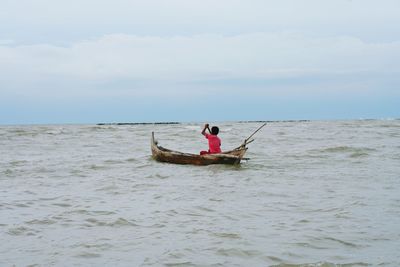 Man on boat in sea against sky