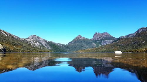 Scenic view of lake and mountains against clear blue sky