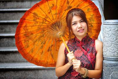 Portrait of smiling young woman holding umbrella