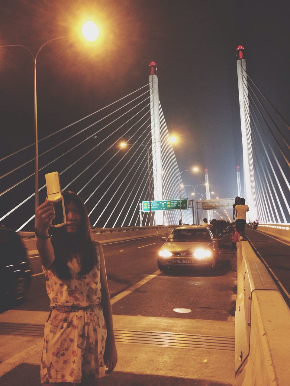 transportation, built structure, illuminated, architecture, street light, night, the way forward, mode of transport, sky, city, travel, bridge - man made structure, suspension bridge, building exterior, lens flare, outdoors, connection, road, travel destinations, engineering