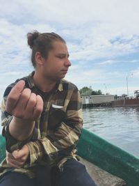 Young man sitting against sky