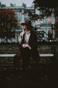 Full length of woman sitting on bench in park