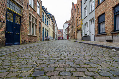 Surface level of footpath amidst buildings against sky