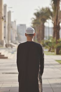 Rear view of man standing on footpath against building