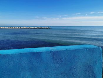 Scenic view of sea against sky. a blu wall is separating from the sea. 