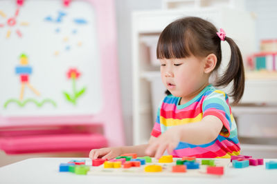 Cute girl looking away while sitting on table