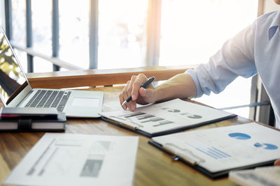 Close-up of hand using laptop on table