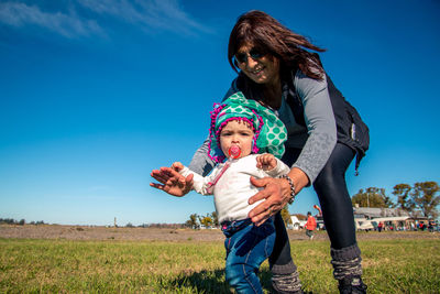 Full length of mother and daughter on field against sky