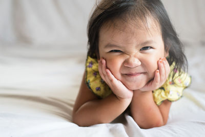 Portrait of cute girl smiling while lying on bed