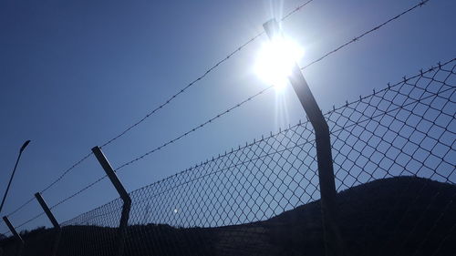 Low angle view of silhouette fence against sky