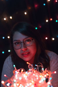 Close-up of young woman with illuminated lights at home