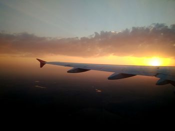 Silhouette airplane wing against sky during sunset