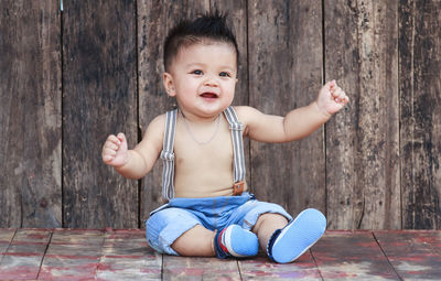 Portrait of cute baby boy sitting on wood