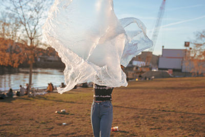 Woman with textile standing on field against sky