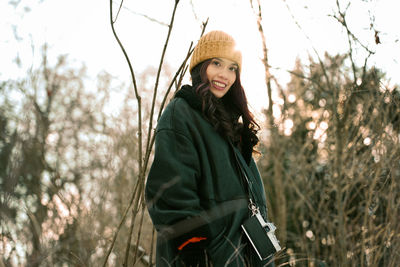 Portrait of young woman standing against plants in winter