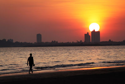 Silhouette people on beach at sunset