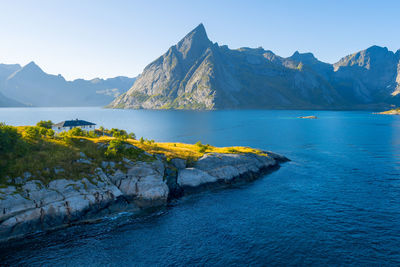 Scenic view of sea and mountains against clear blue sky