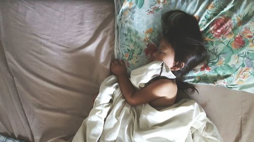 High angle view of girl sleeping on bed at home