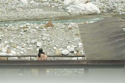 Rear view of woman sitting by swimming pool