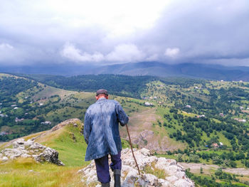 Rear view of man standing on mountain against sky