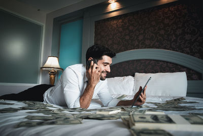 Young man using mobile phone while sitting on bed at home