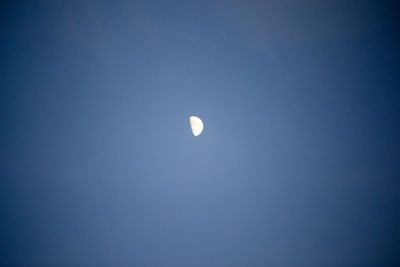 Low angle view of moon against clear blue sky