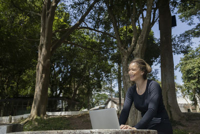 Young woman using a laptop at day time at a green park. mobile phone, technology,