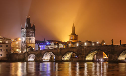 Arch bridge over river against sky at night