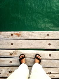 Low section of woman standing on pier over lake