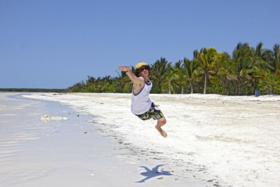 Full length of shirtless boy playing on beach