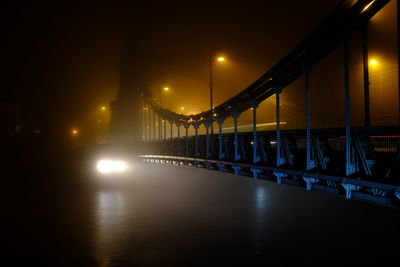 Illuminated bridge over river against sky at night