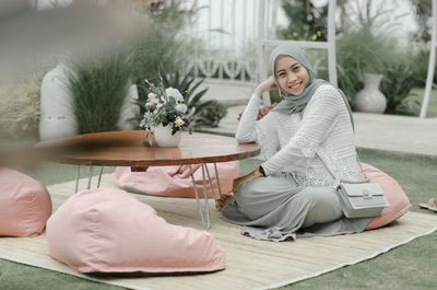 Young woman sitting on bed at home