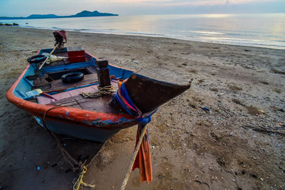 Boat moored on beach against sky