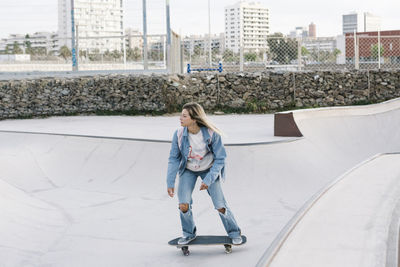 Mid adult woman looking away while riding skateboard in park