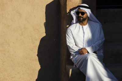 Young man wearing sunglasses standing against wall