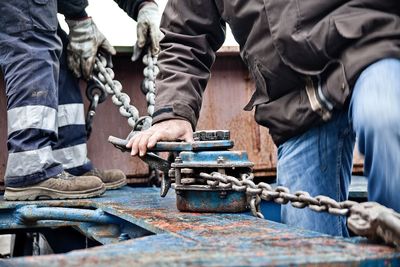 Cropped image of men standing by metallic equipment