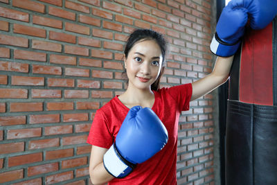 Portrait of young woman wearing boxing glove in gym