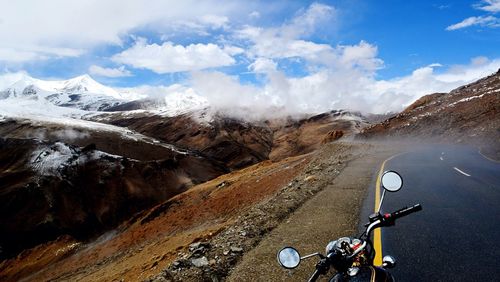 High angle view of motorcycle on street against mountains and cloudy sky