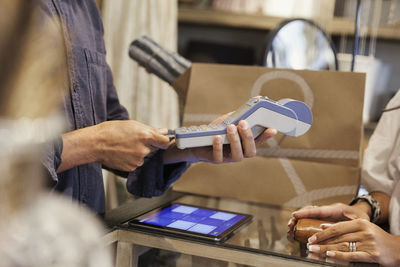 Cropped image of male owner using credit card reader for customer at store