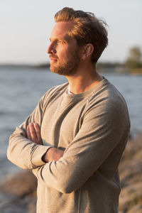 Thoughtful man standing arms crossed on beach