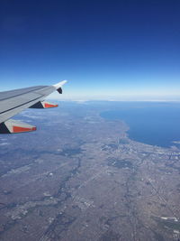 Airplane flying over landscape against blue sky