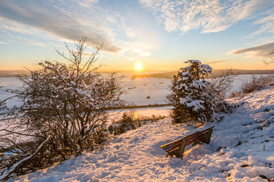 Scenic view of snow covered field against sky during sunset