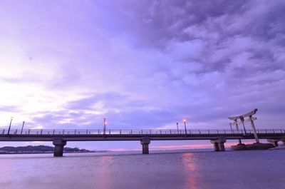 Bridge over sea against cloudy sky