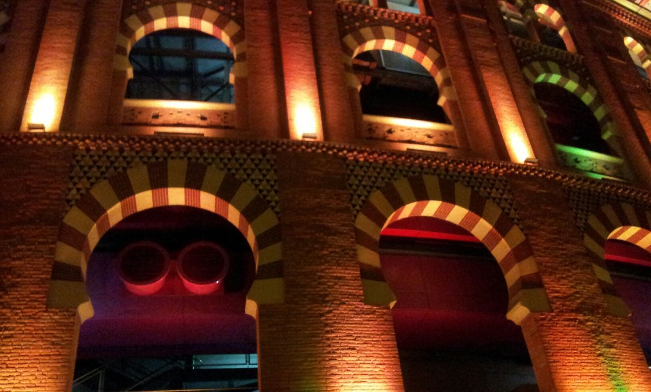 architecture, built structure, building exterior, low angle view, illuminated, arch, window, building, lighting equipment, night, no people, architectural feature, orange color, indoors, residential building, multi colored, red, balcony, brick wall