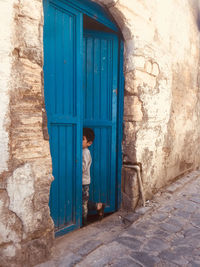 Full length of boy standing against closed door of building