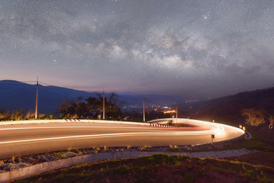 Illuminated road against sky at night