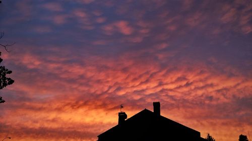 Low angle view of silhouette building against orange sky